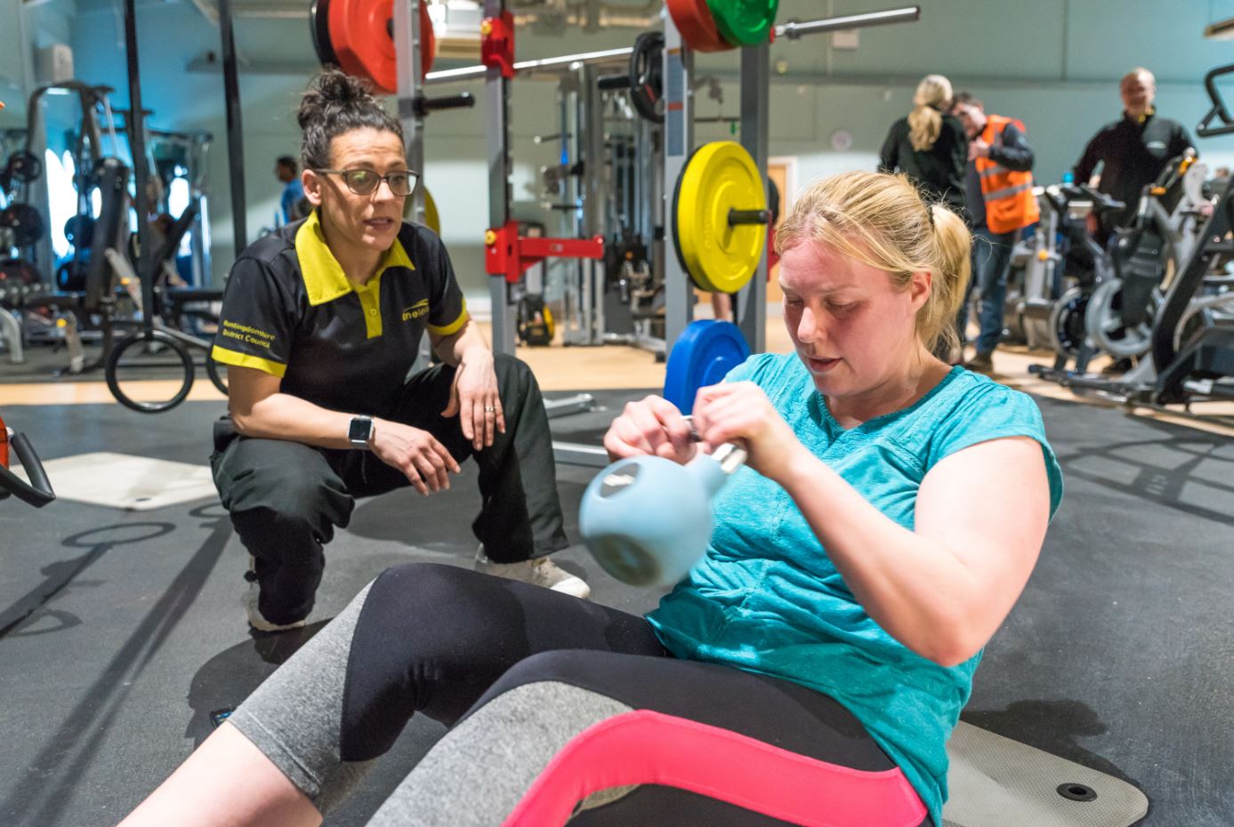 person doing a sit up whilst holding a kettle bell in the gym