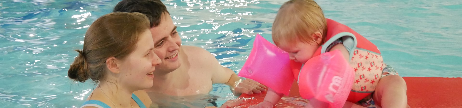 toddler swimming with parents