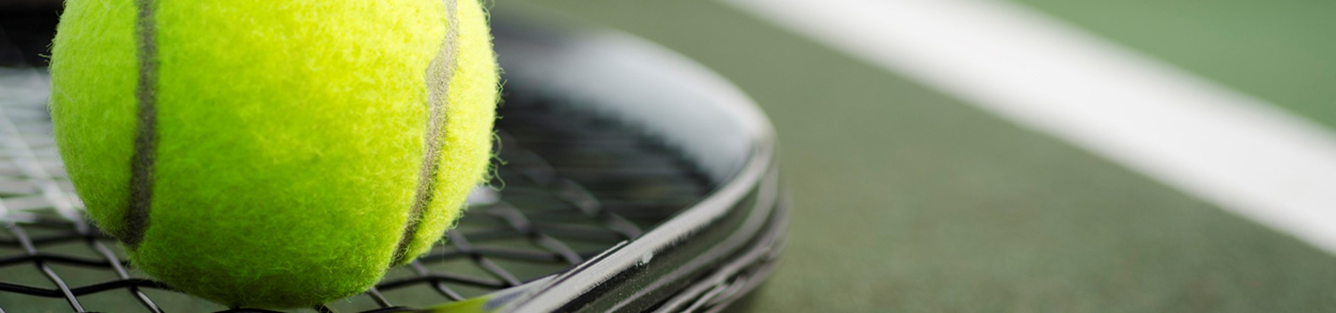 tennis ball balanced on a tennis racket in front of a tennis net